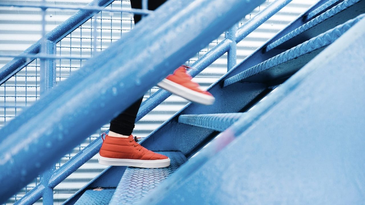 Pessoa subindo em escada de ferro colorida
